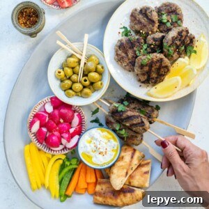 Platter with lamb kofta, tzatziki, olives, sliced vegetables and pita bread