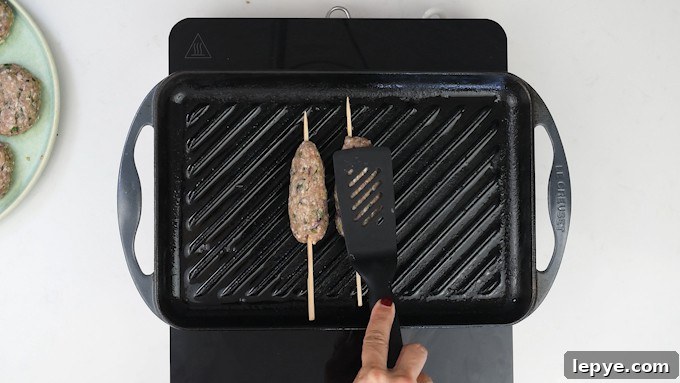 Authentic Lamb Kofta Recipe: Juicy Middle Eastern Meatballs 9 Cooking kofta on a griddle pan