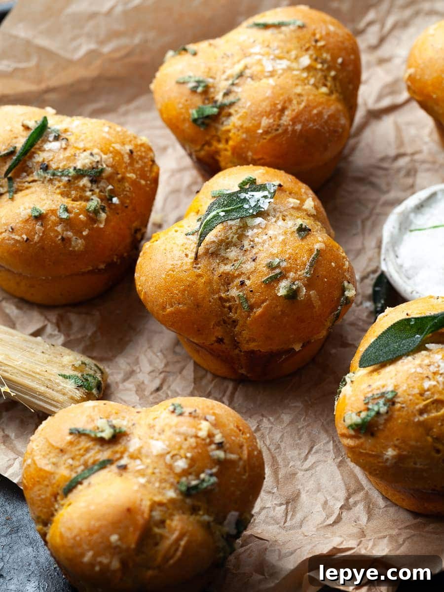 Gluten-Free Pumpkin Dinner Rolls Recipe for Fall Gatherings 9 gluten free pumpkin dinner rolls on a plate topped with flaky sea salt and crispy sage