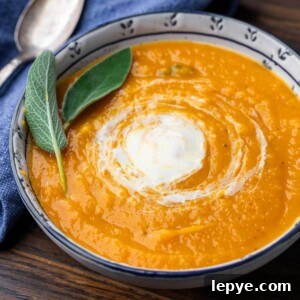 Roasted butternut squash soup in white and blue bowl with sage leaf garnish for featured image.