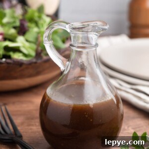 Classic Balsamic Vinaigrette Dressing Recipe 6 balsamic vinaigrette in a glass cruet in front of a bowl of spring mix lettuce