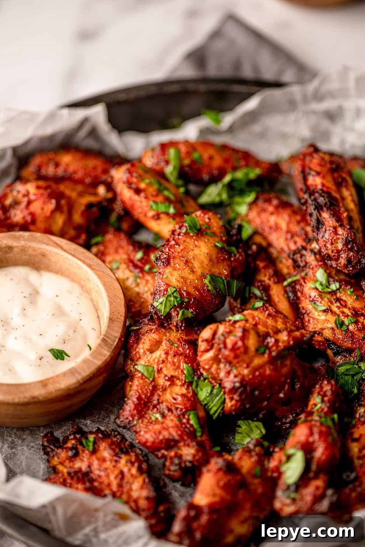 How to Reheat Chicken Wings: Air Fryer, Oven, or Stovetop 3 Wings next to a wooden bowl of blue cheese.