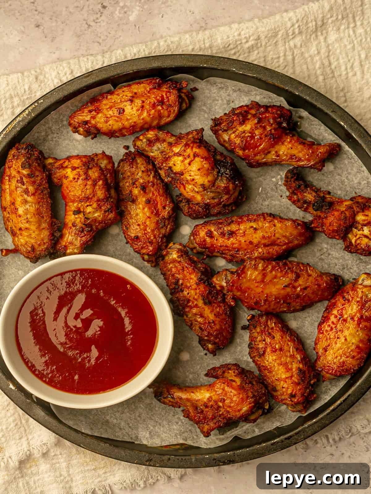 How to Reheat Chicken Wings: Air Fryer, Oven, or Stovetop 5 Dry wings on a platter next to a bowl of barbecue sauce.