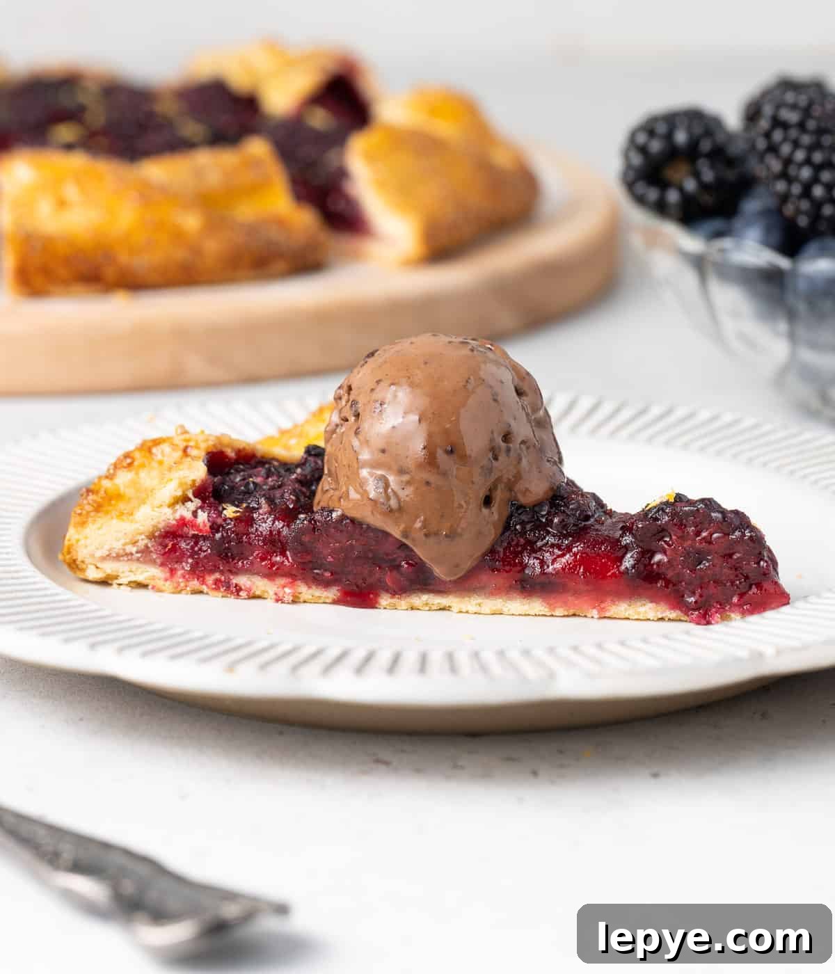 One slice in a small white plate topped with a scoop of chocolate ice cream.