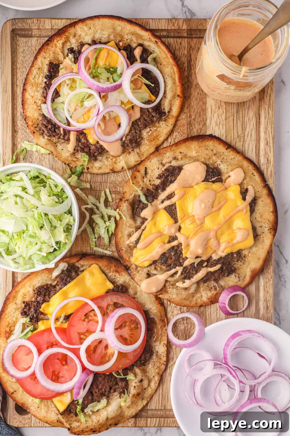 Smash Burger Tacos on Cutting Board with the fixings and burger sauce