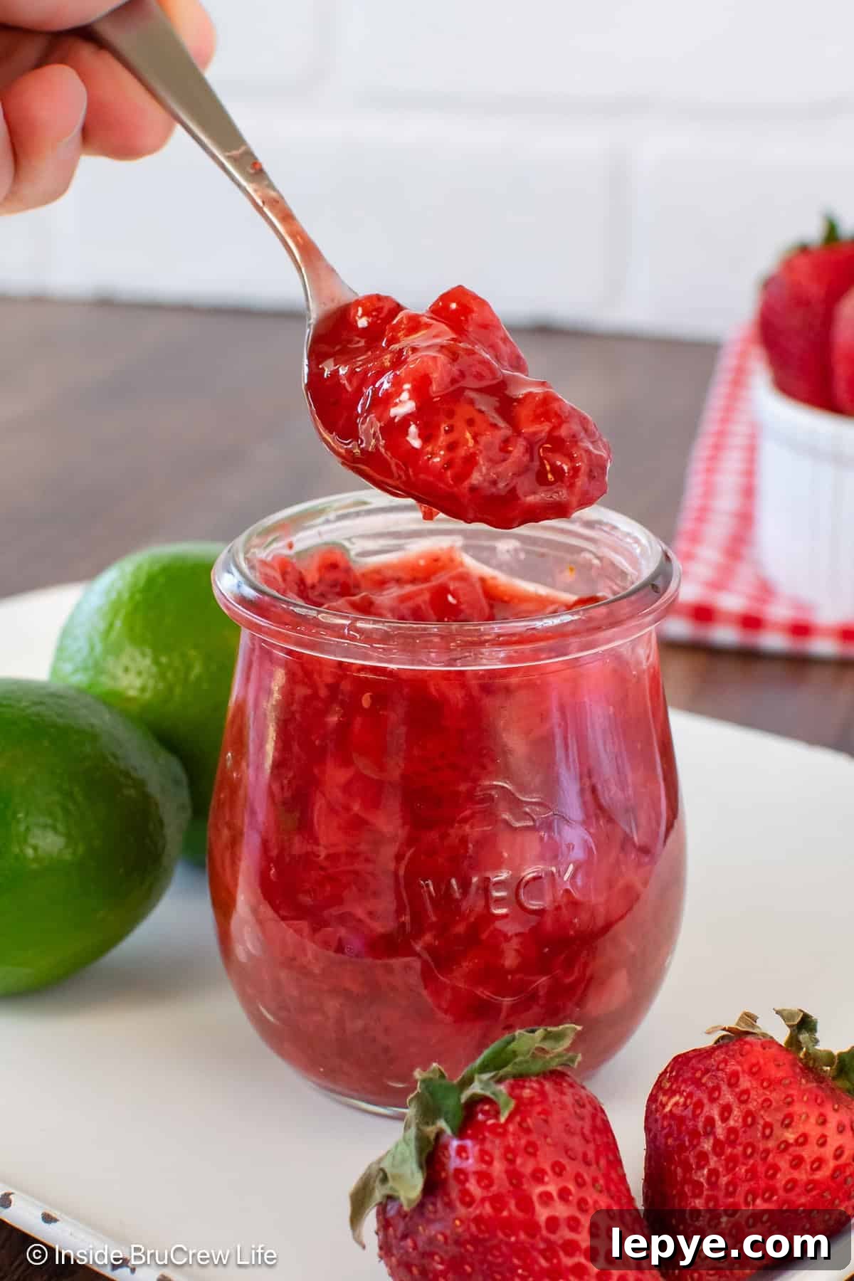 Homemade Strawberry Sauce Recipe for Desserts & Pancakes 2 A jar of strawberry sauce with a spoonful being lifted out of it.