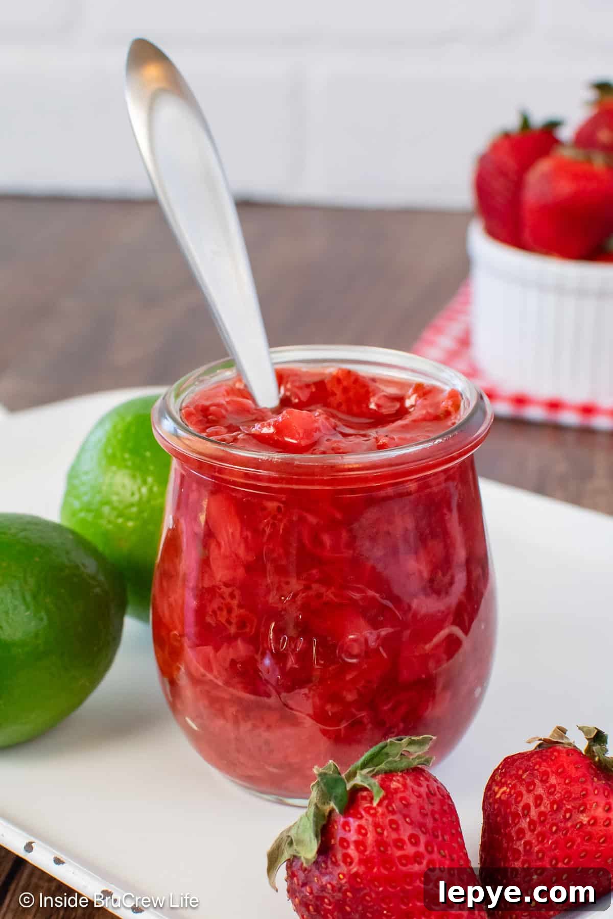 Homemade Strawberry Sauce Recipe for Desserts & Pancakes 7 A clear jar of easy strawberry sauce with a spoon in it.
