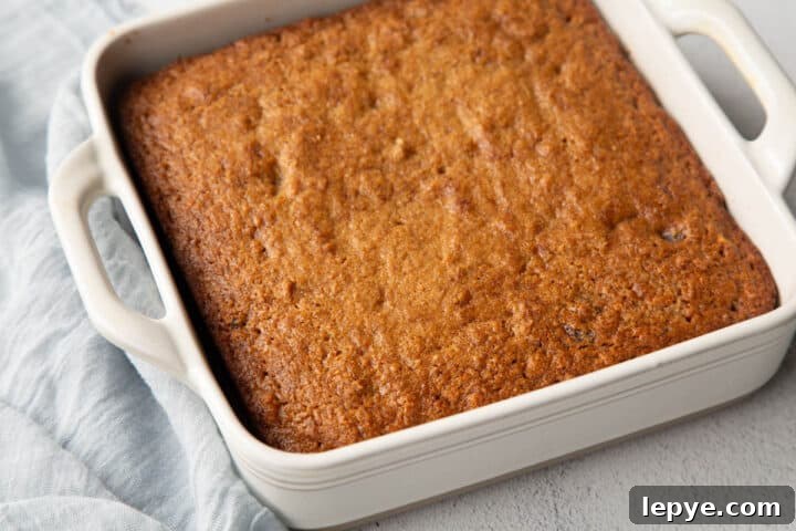 golden brown applesauce cake in a white dish with handles.
