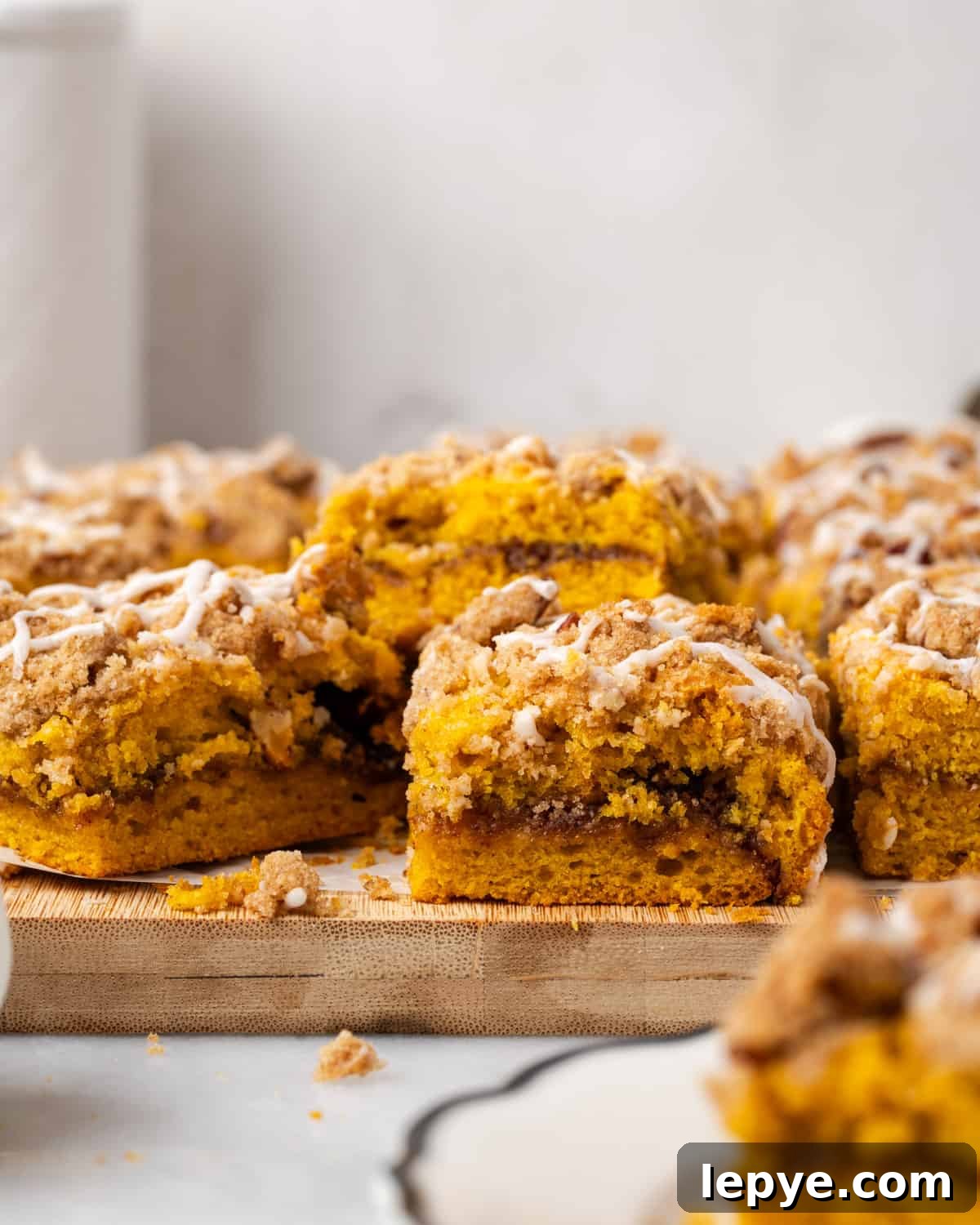 Squares of pumpkin coffee cake scattered on a wood cutting board.