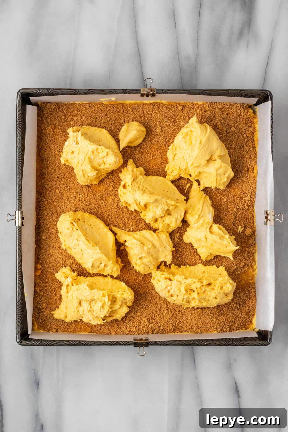 Square baking pan filled with pumpkin coffee cake batter.