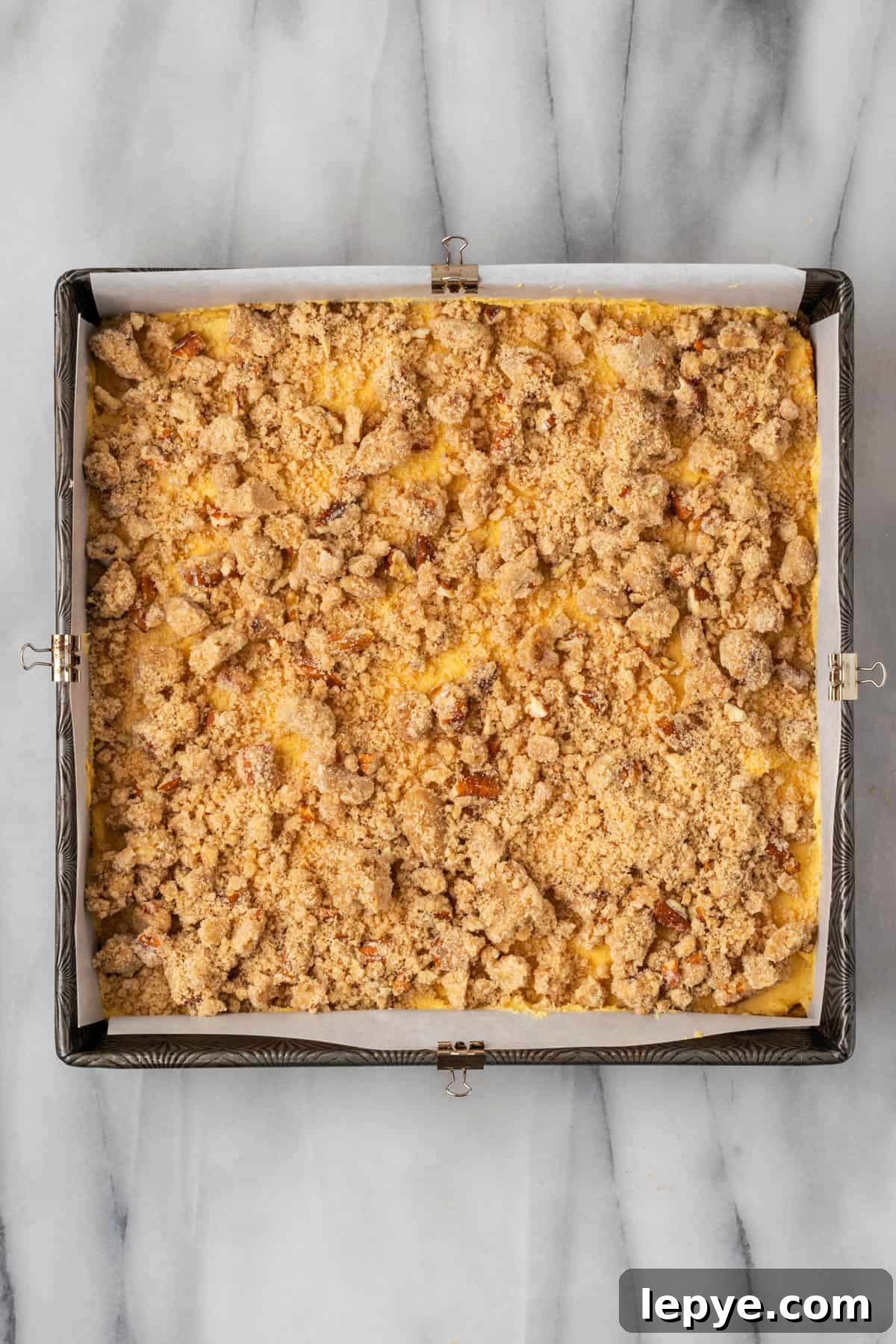 Unbaked pumpkin coffee cake covered with a crumb topping. 
