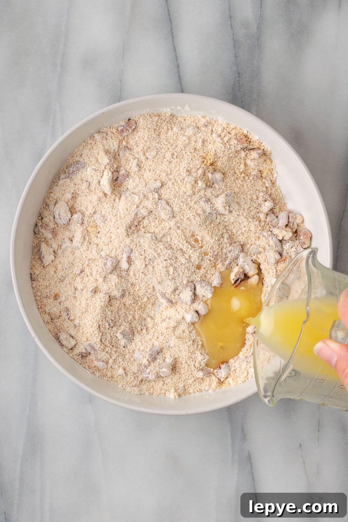 Melted butter being poured into the dry streusel ingredients.