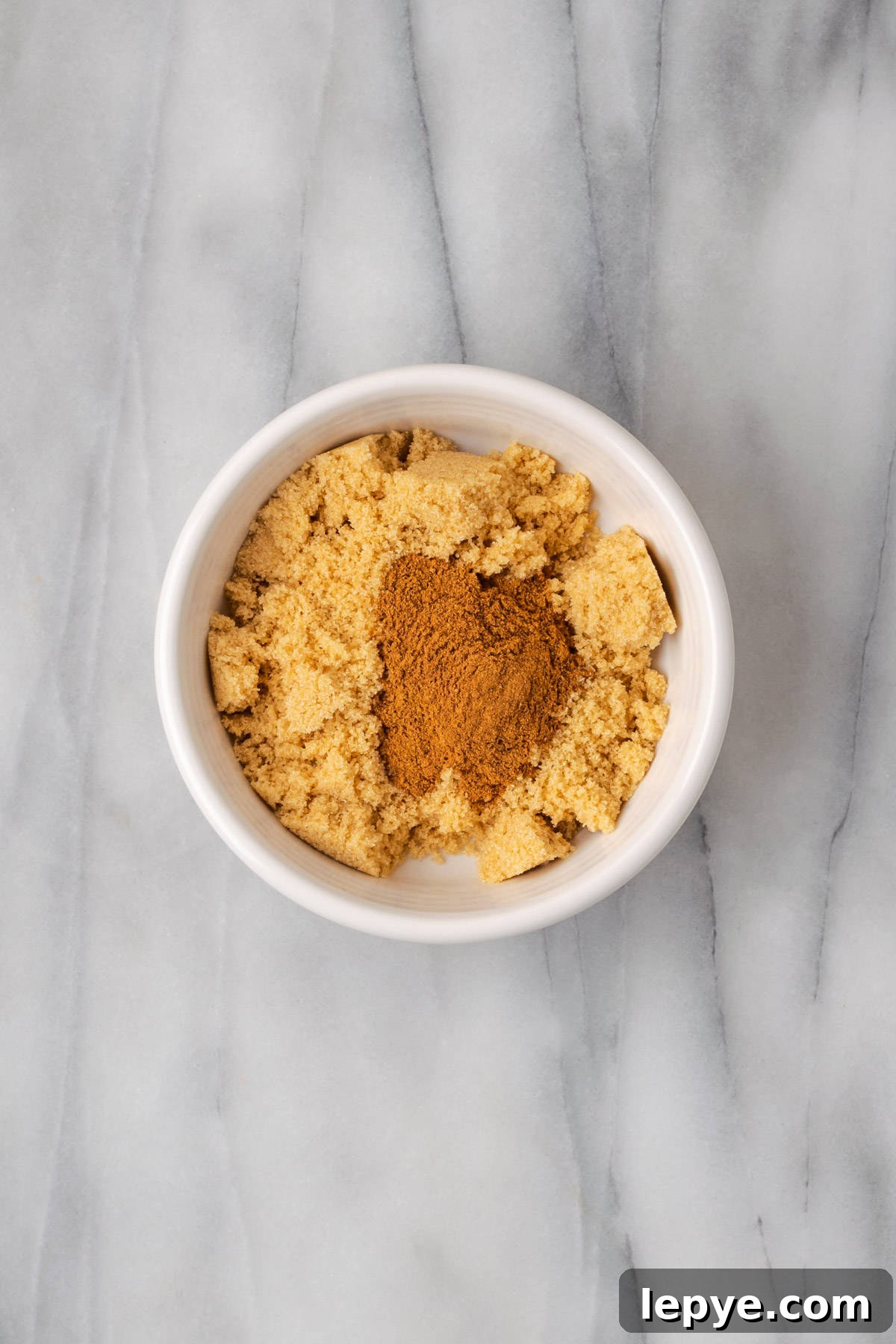 Brown sugar and pumpkin pie spice combined in a small white bowl. 