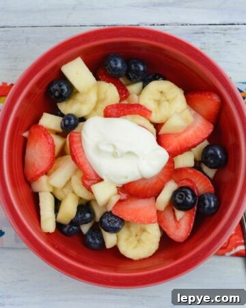Fruit salad with crème fraiche in a red bowl.