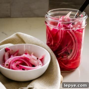 Pickled red onions in a white bowl and in a clear jar beside it.