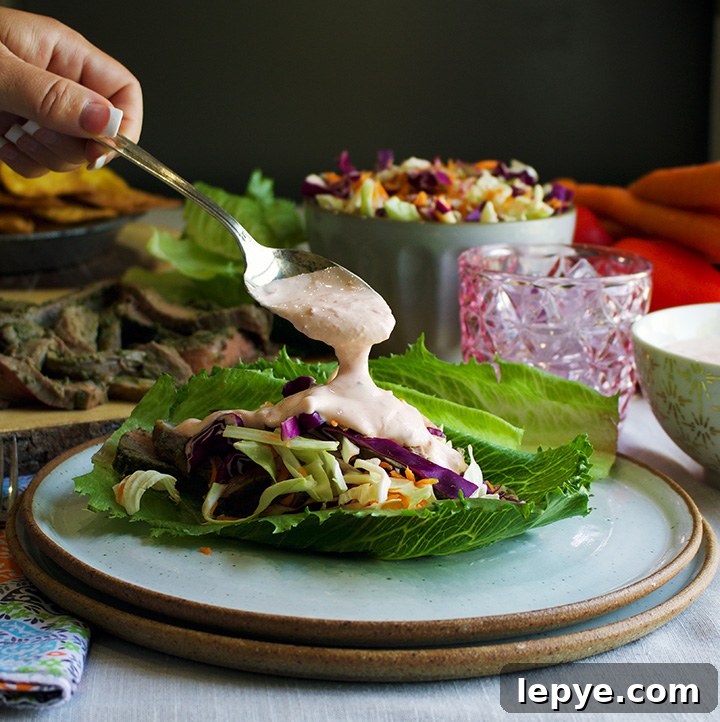 Steak Salad Wraps with Tangy Chimichurri and Crisp Veggies 5 Spooning chili yogurt sauce over steak salad wraps.