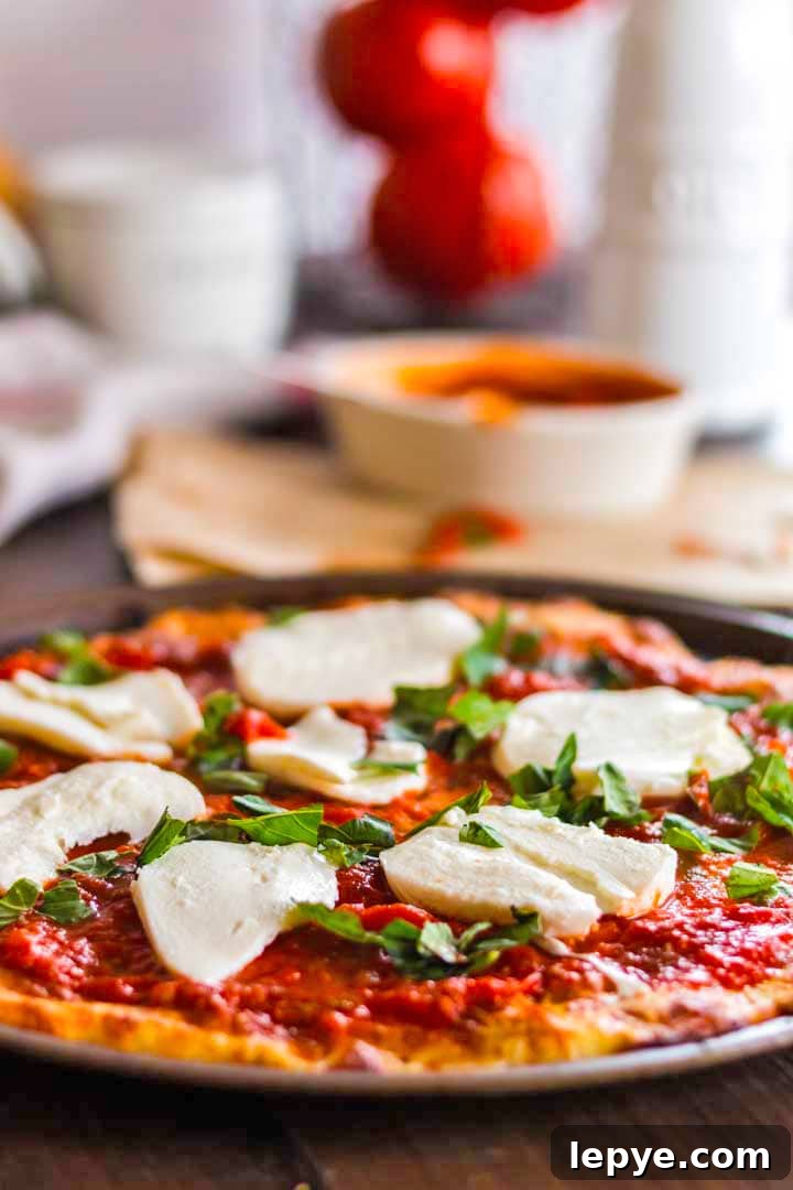 Keto pizza topped with Mozzarella cheese and steam rising from it.