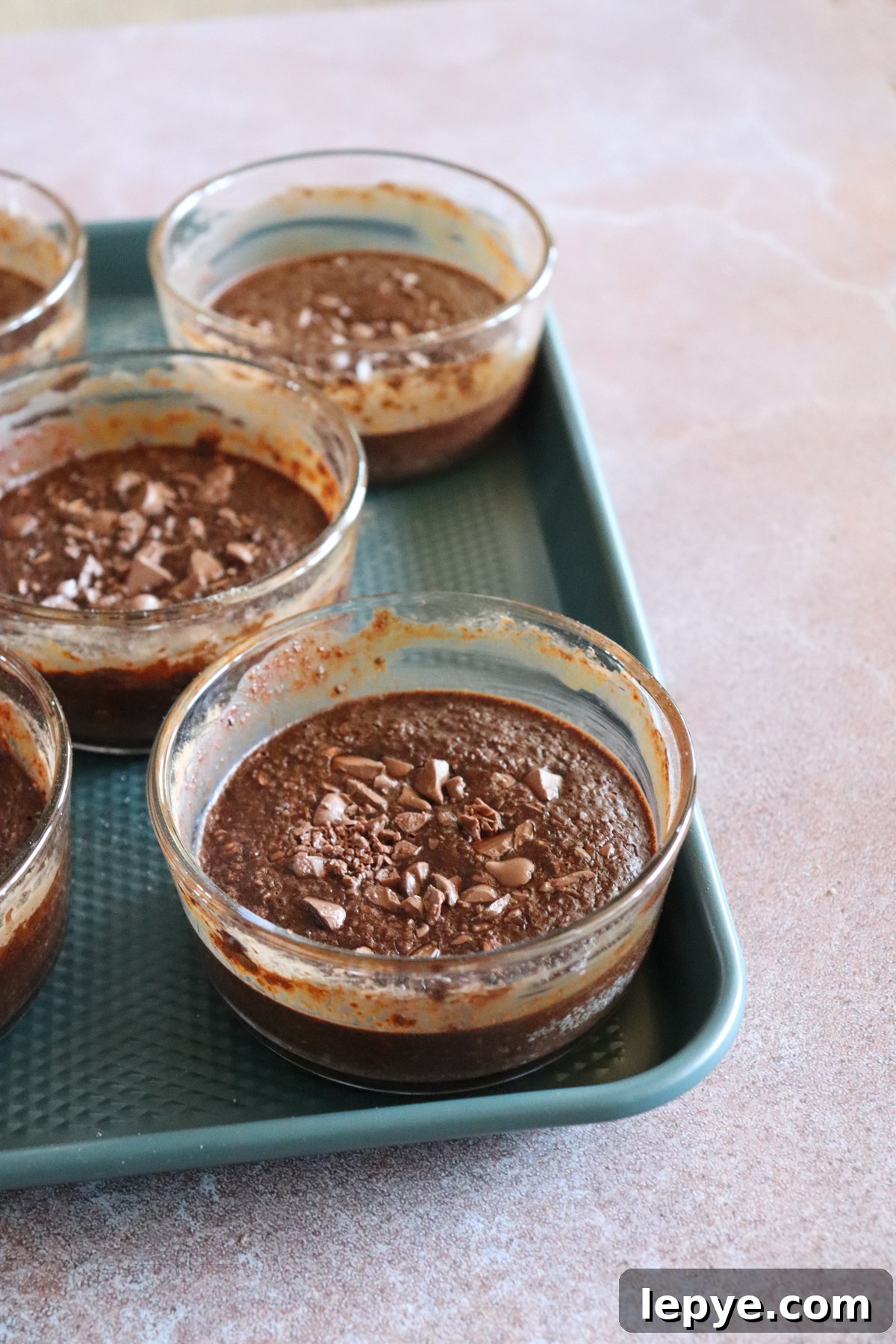 Chocolate baked oats showing sheet pan with 5 glass bowls containing chocolate baked oats.