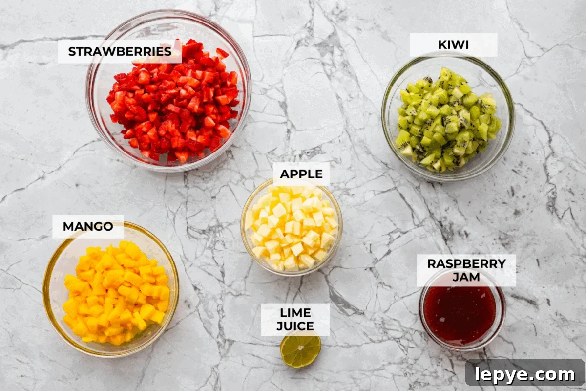 Vibrant fruit salsa is a fresh, juicy twist on your favorite snack! Sweet berries, tropical mango, and a splash of lime always steal the spotlight! Especially when served with crispy cinnamon chips! Overhead shot of labeled ingredients.