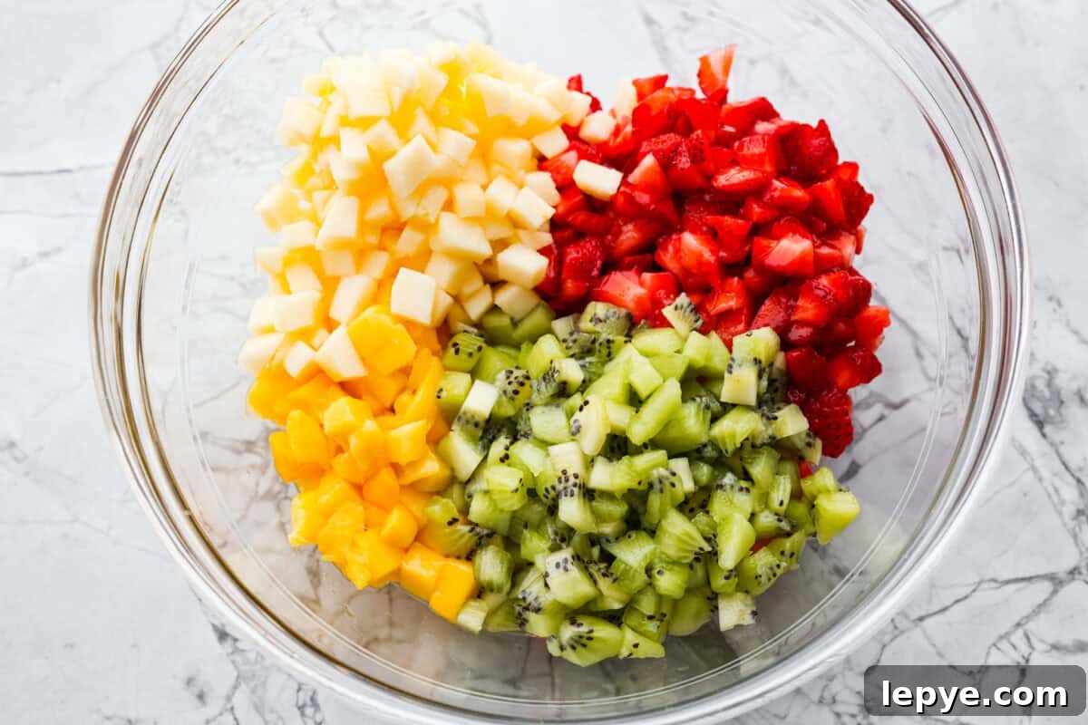 Vibrant fruit salsa is a fresh, juicy twist on your favorite snack! Sweet berries, tropical mango, and a splash of lime always steal the spotlight! Especially when served with crispy cinnamon chips! Diced fruit added to a bowl.