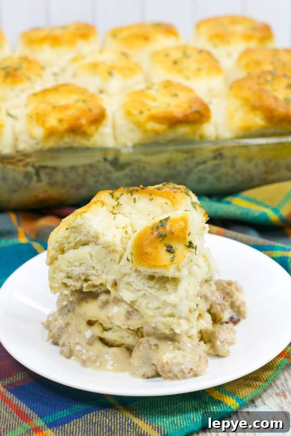 a plate piled high with biscuits and gravy casserole with the whole casserole in the background.