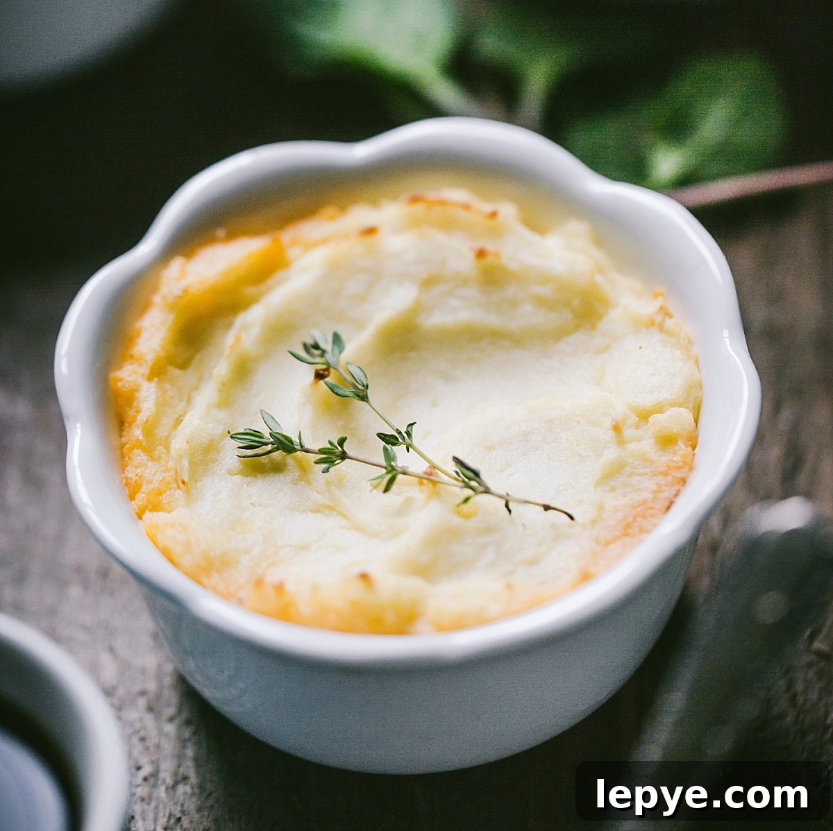close up of golden guinness shepherds pie with tiny sprig of thyme on top