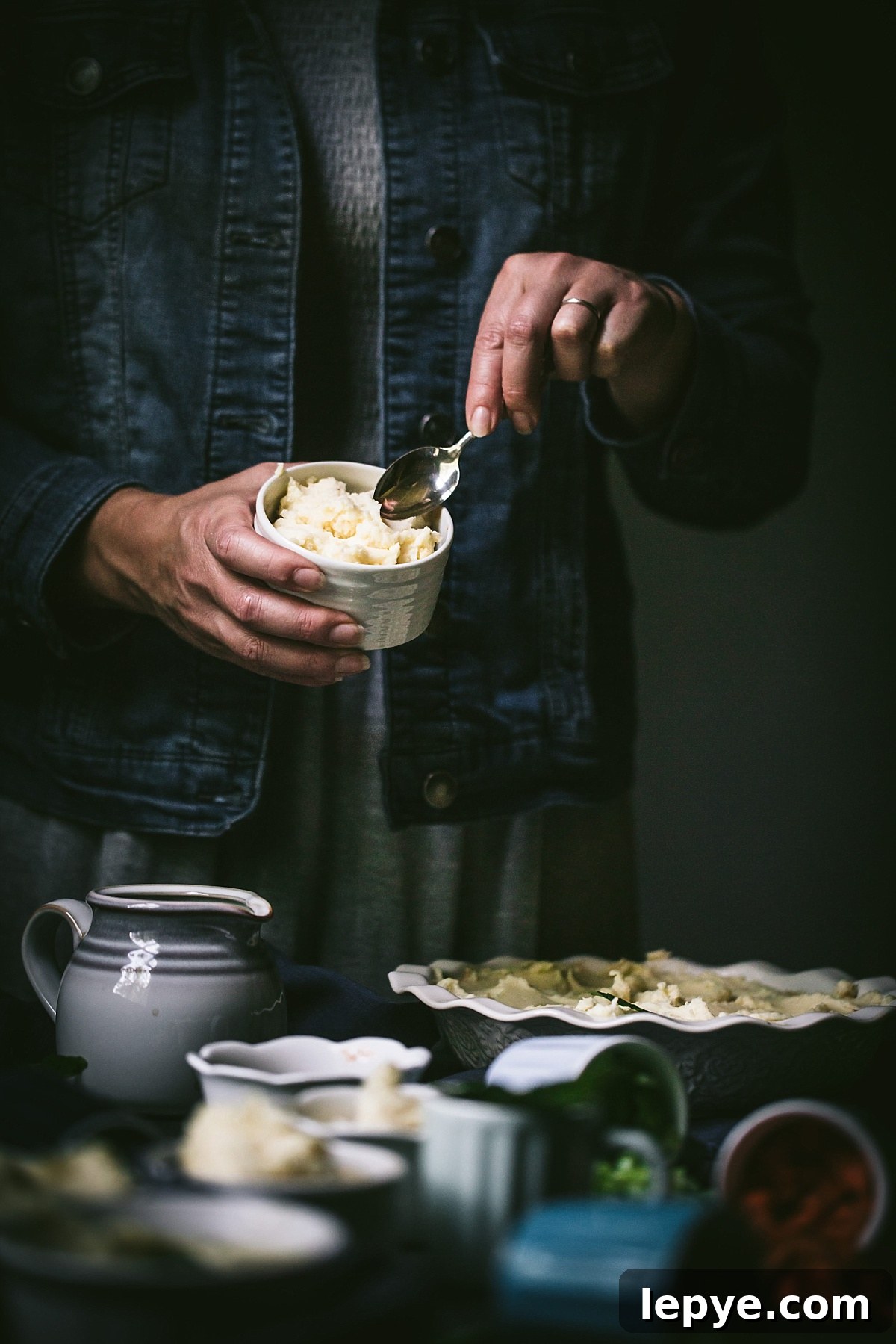 girl in denim jacket smooths mashed potatoes on top of cottage pie