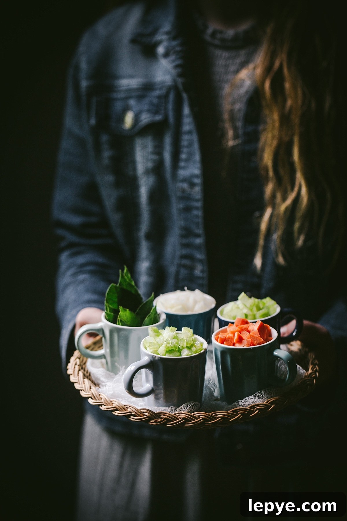 girl holds tray of carrots, celery, onion, and bay leaves for guinness shepherds pie