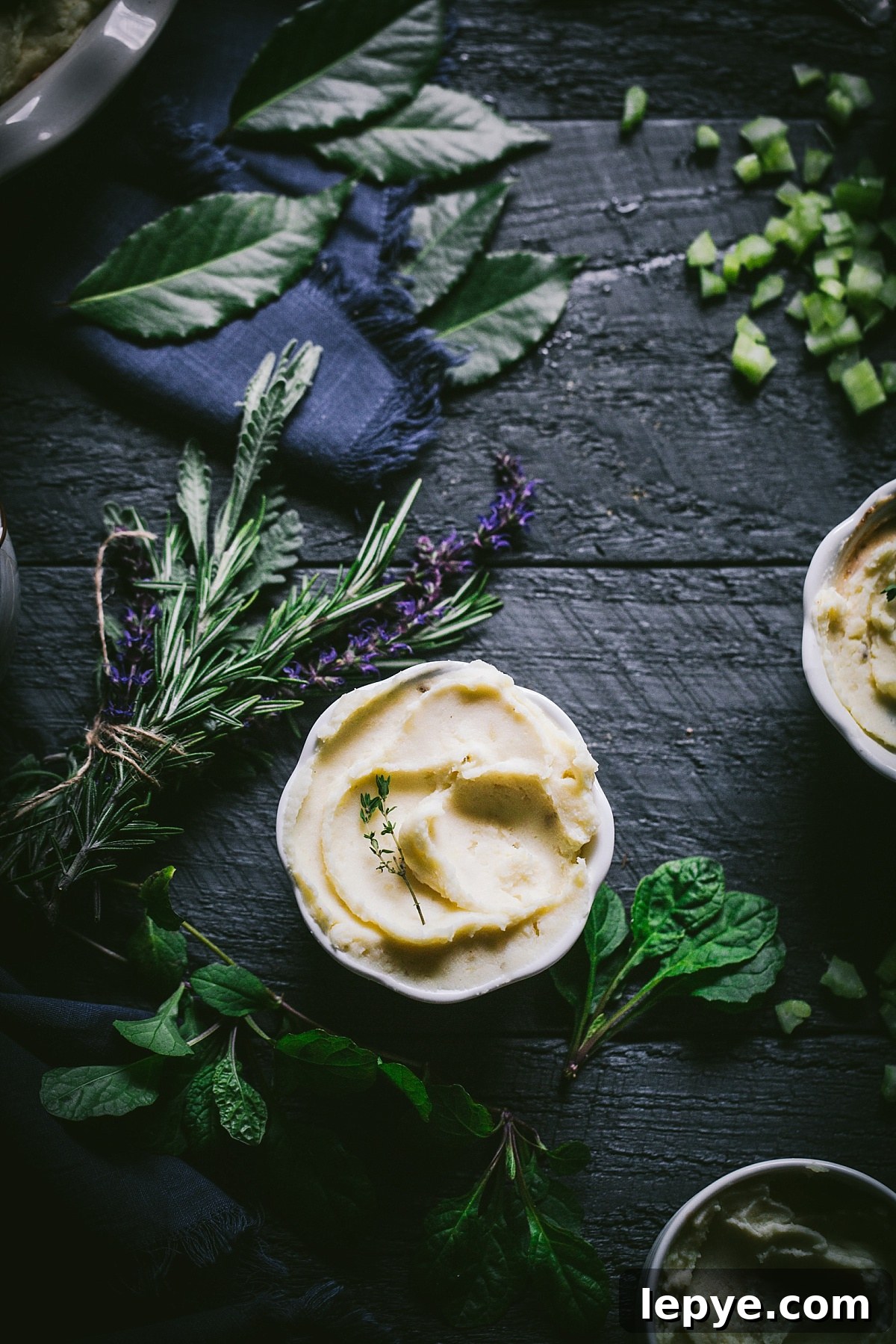 overhead shot of individual serving of guinness shepherds pie topped with lovely thick swirled mashed potatoes and surrounded with fresh herbs