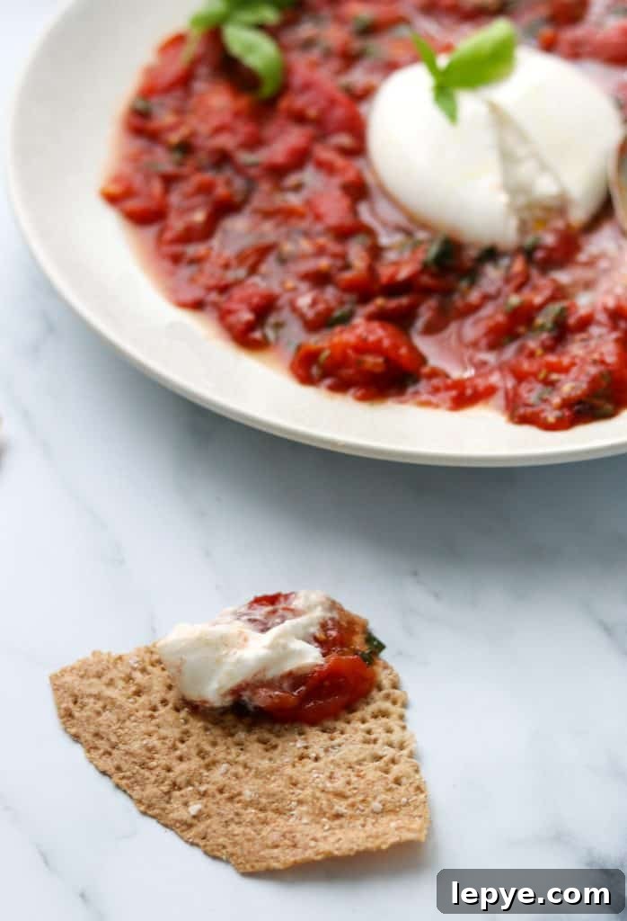 Smoky Grilled Tomatoes with Burrata and Crispy Crispbread 5 A plate of grilled tomatoes and burrata with a piece of crispbread