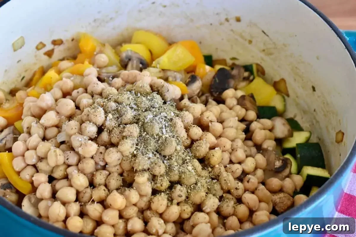 Stovetop Pan-Roasted Vegetables with Garlic White Beans 8 All of the cooked vegetables in a pot with garbanzo beans and seasoning on top.