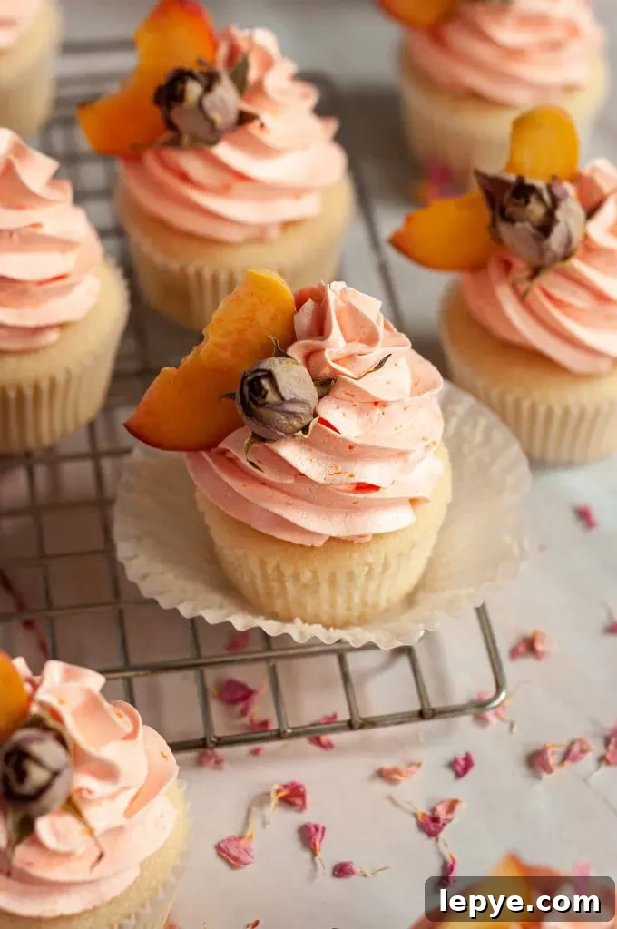 Lemon Raspberry Cupcakes with Gluten-Free & Dairy-Free Option 10 Peach rose cupcakes with a peachy orange frosting swirl and a slice of fresh peach and dried rose on top for decor.