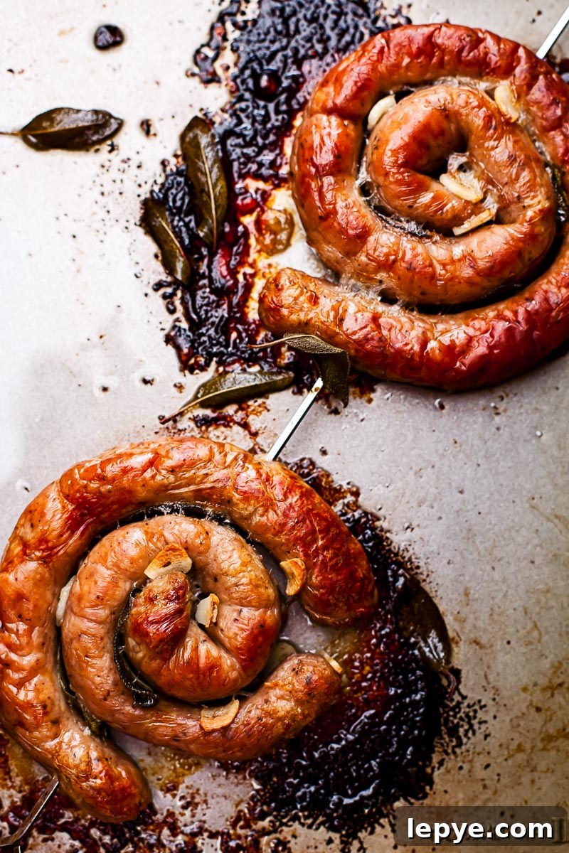 Catherine Wheel Sausages with Garlic & Sage: Crispy Herb-Roasted Recipe 3 two sausage wheels on a skewer on a baking sheet