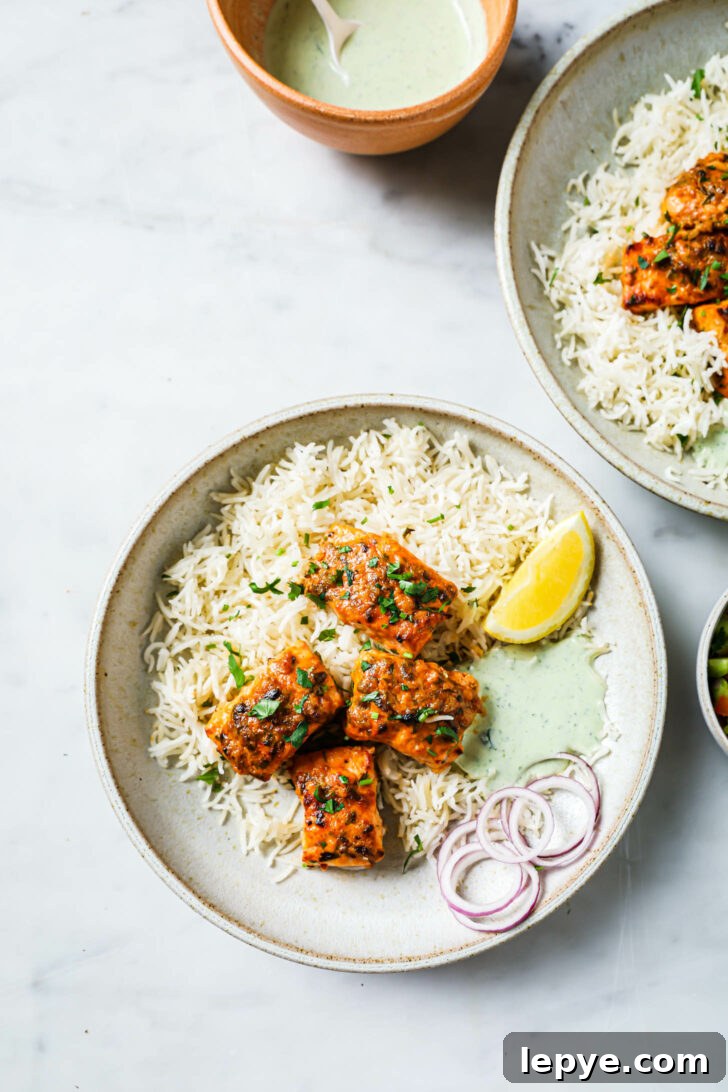 25-Minute Salmon Tikka Recipe: Quick Spiced Fish Tikka 11 Top view of a plate of Salmon Tikka with rice, raita, onion and lemon.