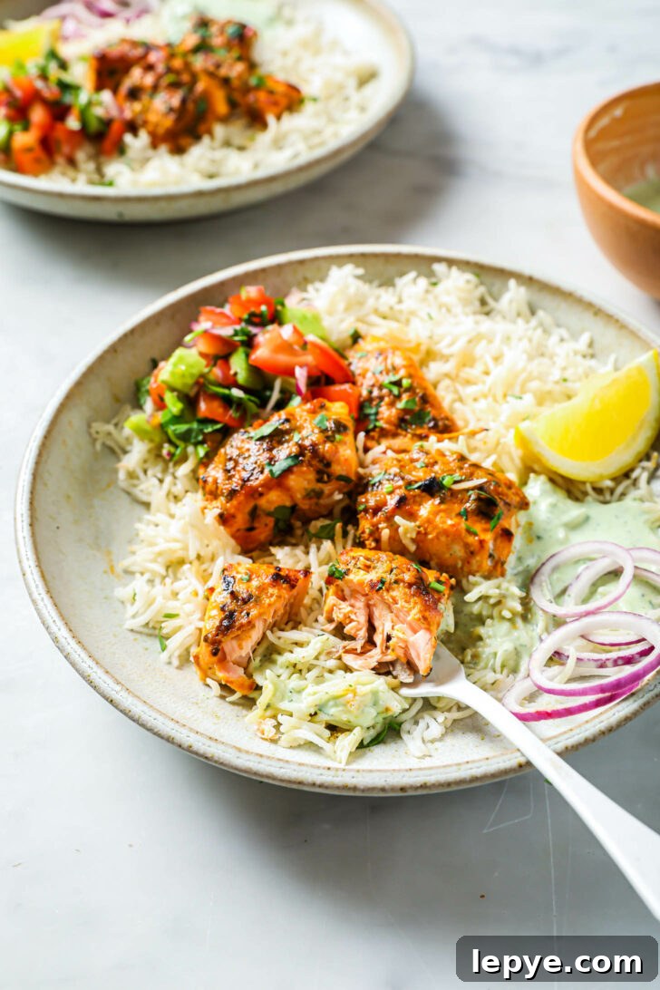 25-Minute Salmon Tikka Recipe: Quick Spiced Fish Tikka 12 Side view of partially eaten plate of Salmon Tikka with rice, vegetables, onion and lemon.