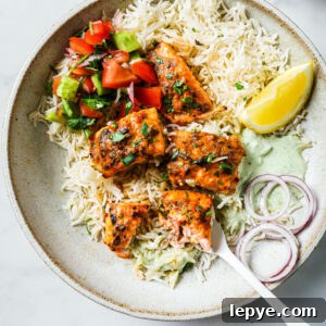 25-Minute Salmon Tikka Recipe: Quick Spiced Fish Tikka 13 Top view of a partially eaten plate of Salmon Tikka with rice, vegetables, onion and lemon.