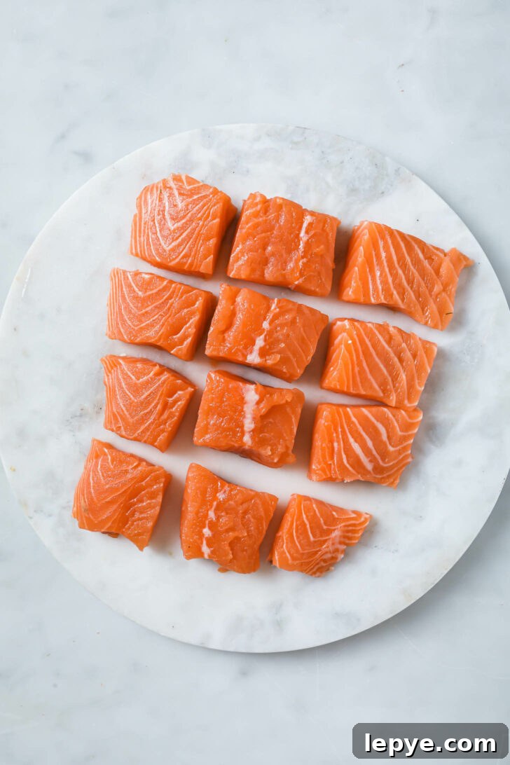 25-Minute Salmon Tikka Recipe: Quick Spiced Fish Tikka 5 Raw salmon cut into cubes on a marble slab.