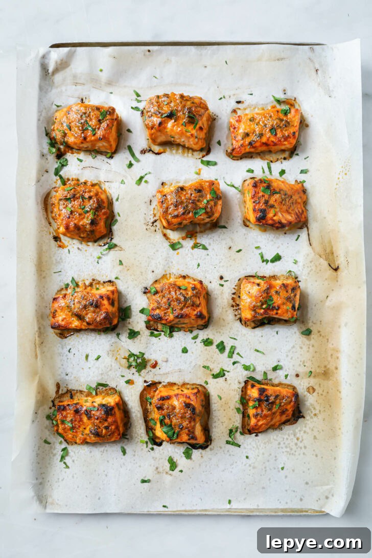 25-Minute Salmon Tikka Recipe: Quick Spiced Fish Tikka 10 A parchment covered sheet pan with baked Salmon Tikka sprinkled with parsley.