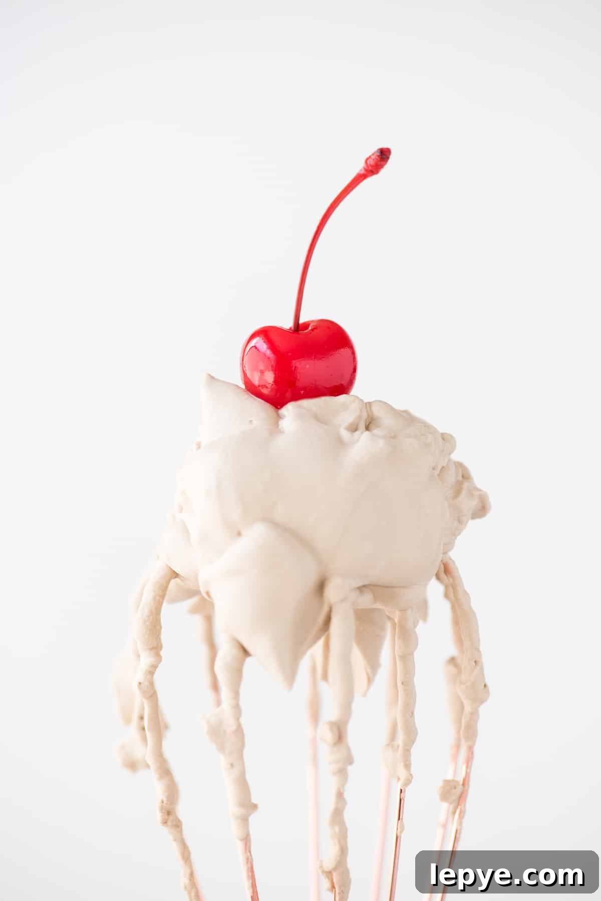 root beer whipped cream with maraschino cherry on a rose gold whisk