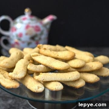 Keto Ladyfingers Recipe: Low-Carb Savoiardi for Desserts 4 A glass plate filled with keto lady fingers is placed on a dark surface. A floral teapot is in the background.