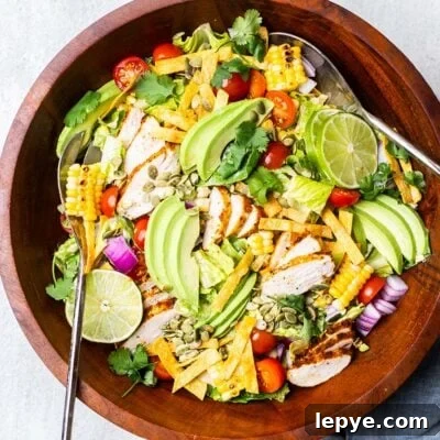 A vibrant Mexican Salad with Marinated chicken breast shown in a wooden bowl.