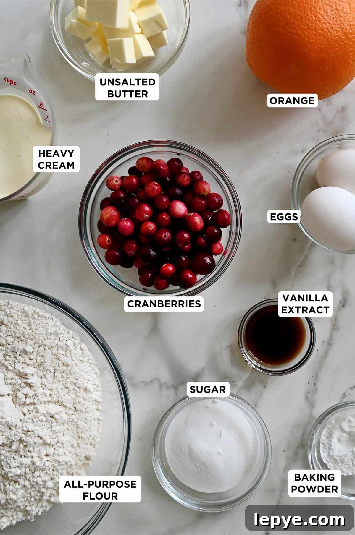 Different sizes of glass bowls containing the ingredients to make cranberry orange scones.