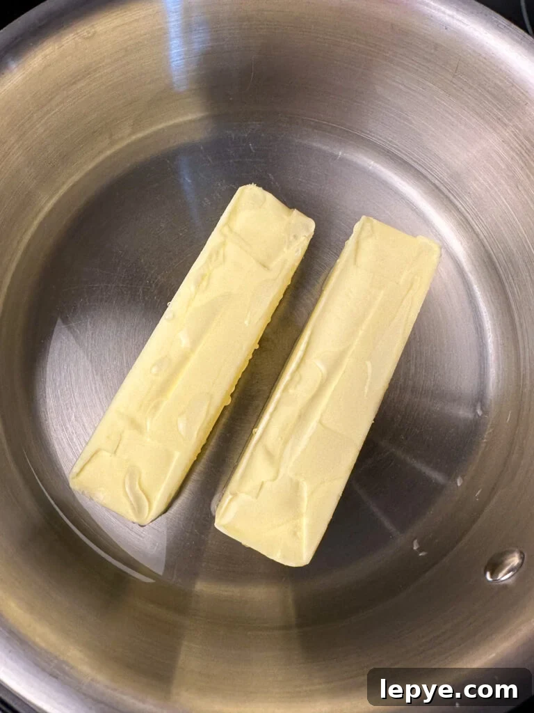 Southern-Style White Texas Sheet Cake Recipe 5 Two sticks of butter in a silver pan.