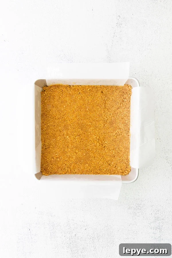 graham cracker crust in an 8x8 square metal pan lined with parchment paper