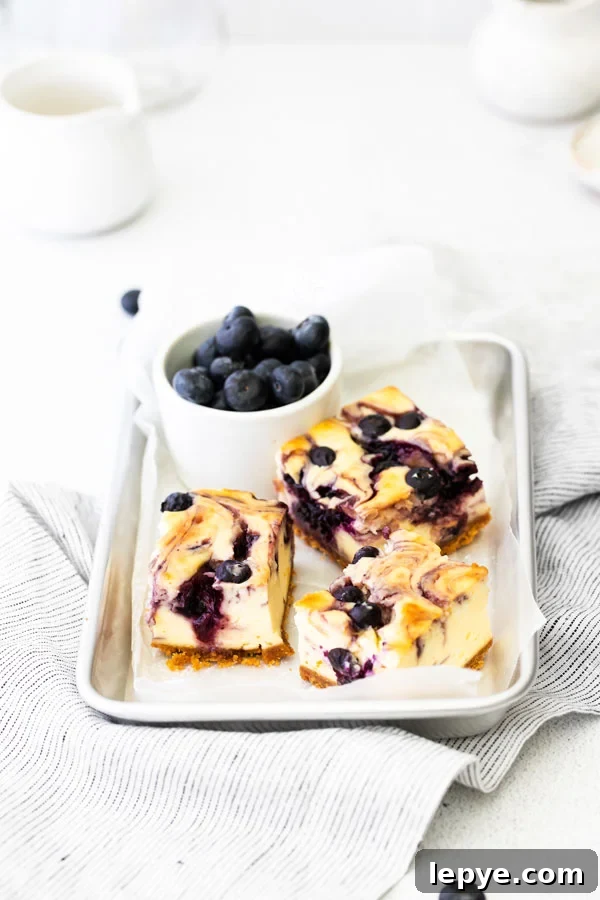3 Gluten Free Blueberry Cheesecake Bars on a parchment paper lined 1/8 sheet pan