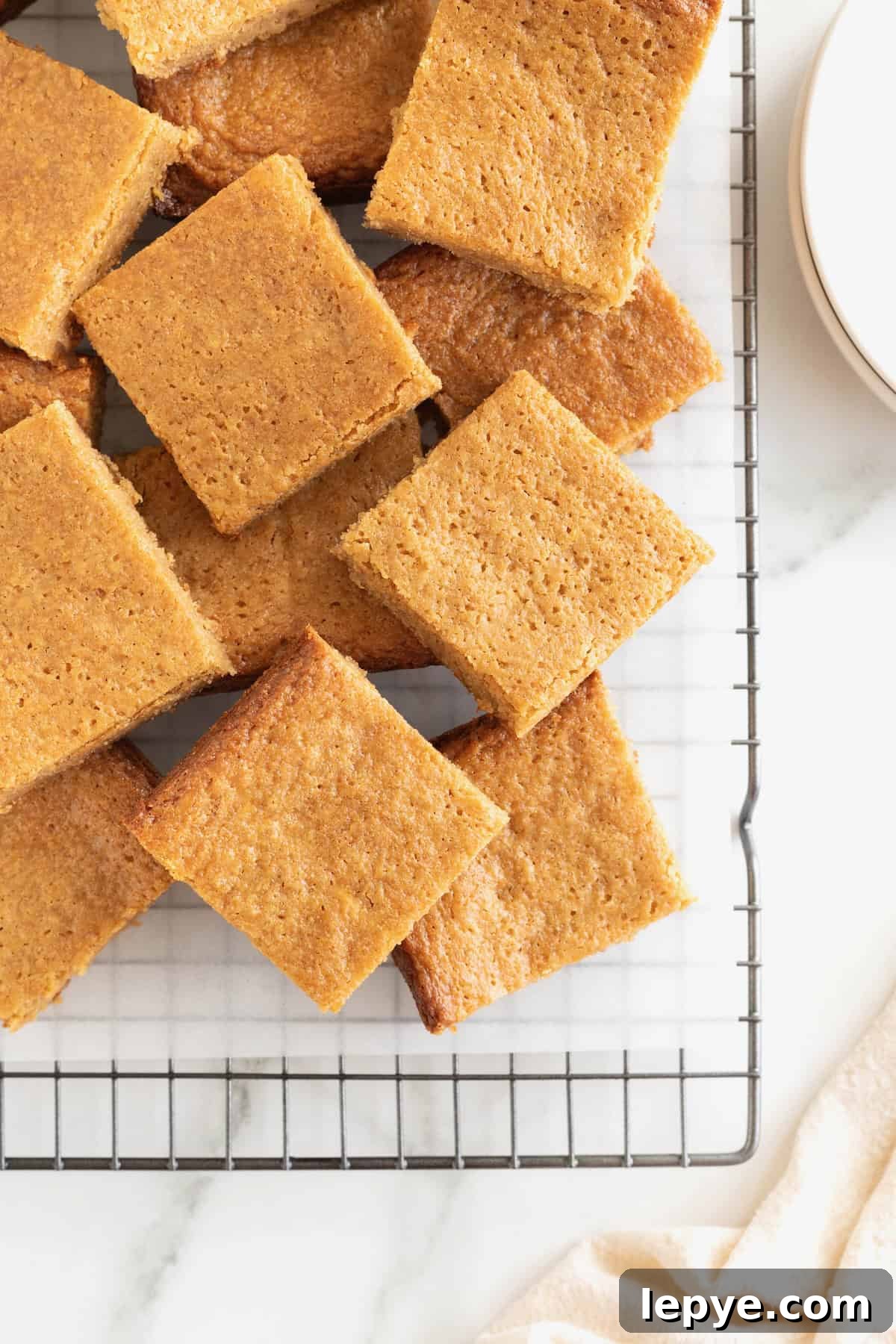 A pile of peanut butter blondies on a parchment lined cooling rack.
