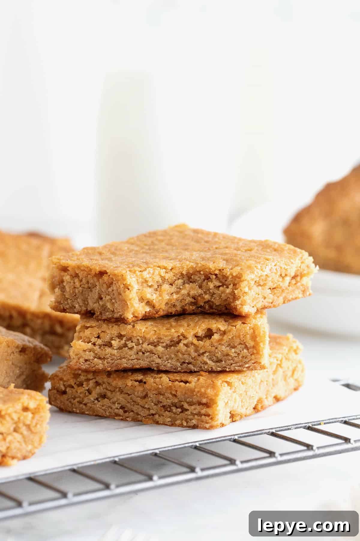 Three peanut butter blondies stacked on a parchment lined cooling rack.