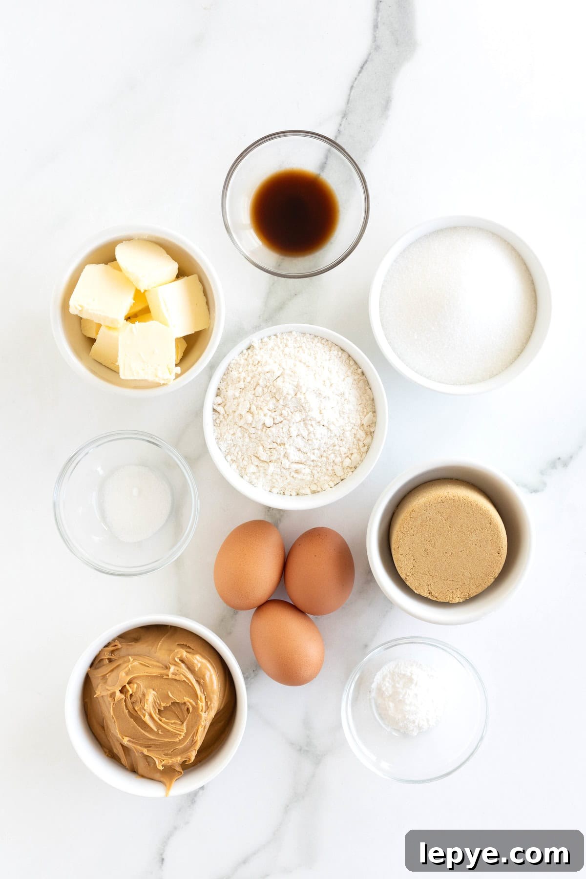 Ingredient to make peanut butter blondies in small glass dishes on a white marble counter.