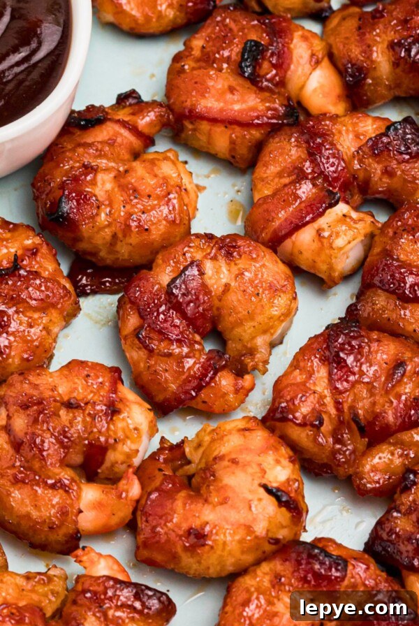 Crispy Oven-Roasted Potatoes with Garlic and Herbs 12 Crispy bacon wrapped around shrimp, coated with BBQ sauce mixture, on a light green plate with lemon slices and serving tongs on the table.