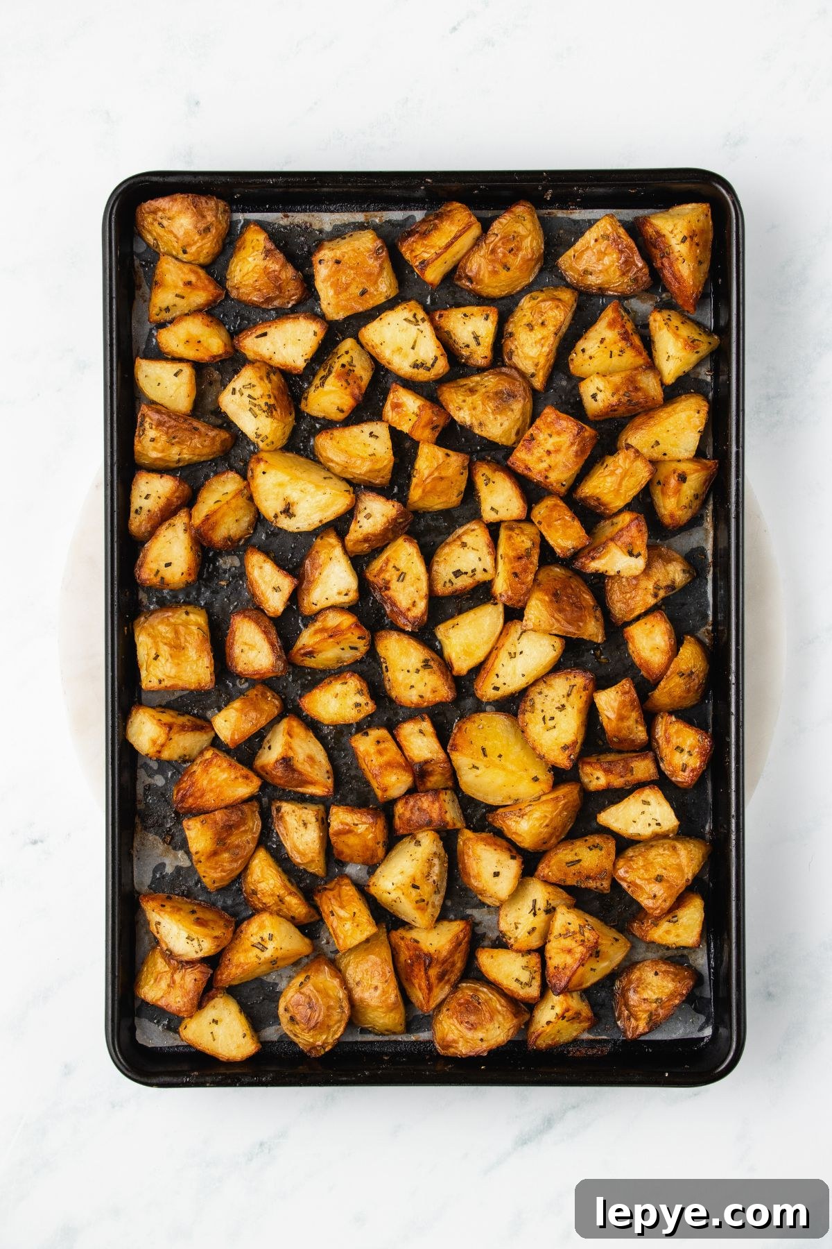 Crispy Oven-Roasted Potatoes with Garlic and Herbs 6 Golden crispy potatoes baked on a baking sheet.